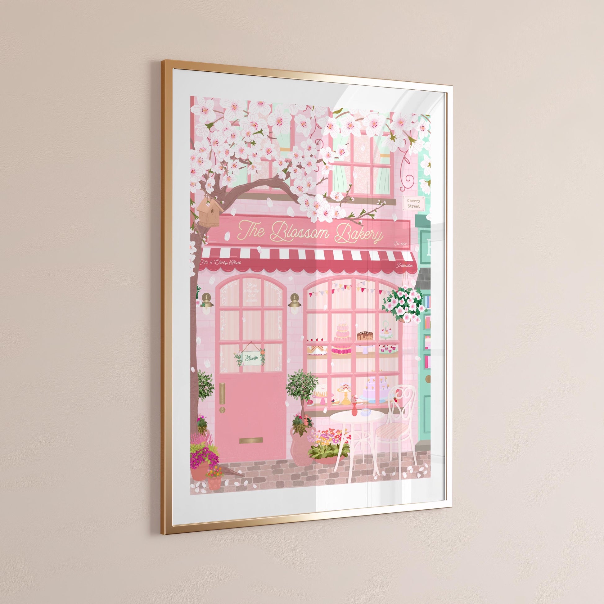 Framed artwork of a pink bakery shop with cherry blossoms on a beige wall.