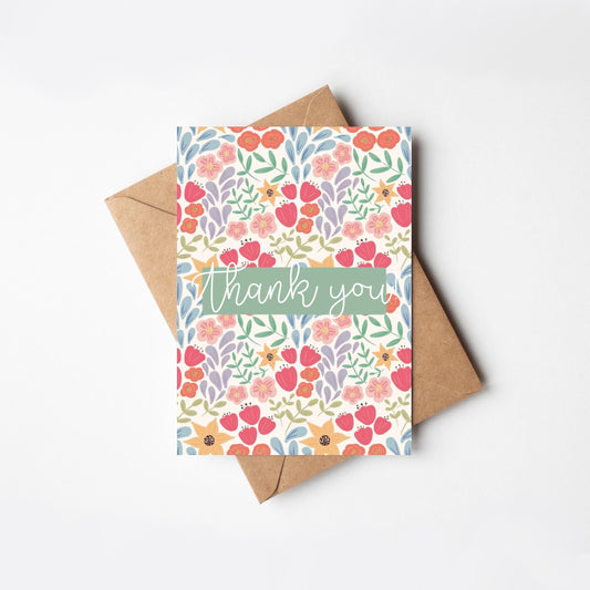 Floral card with 'thank you' text and a brown envelope on a white background