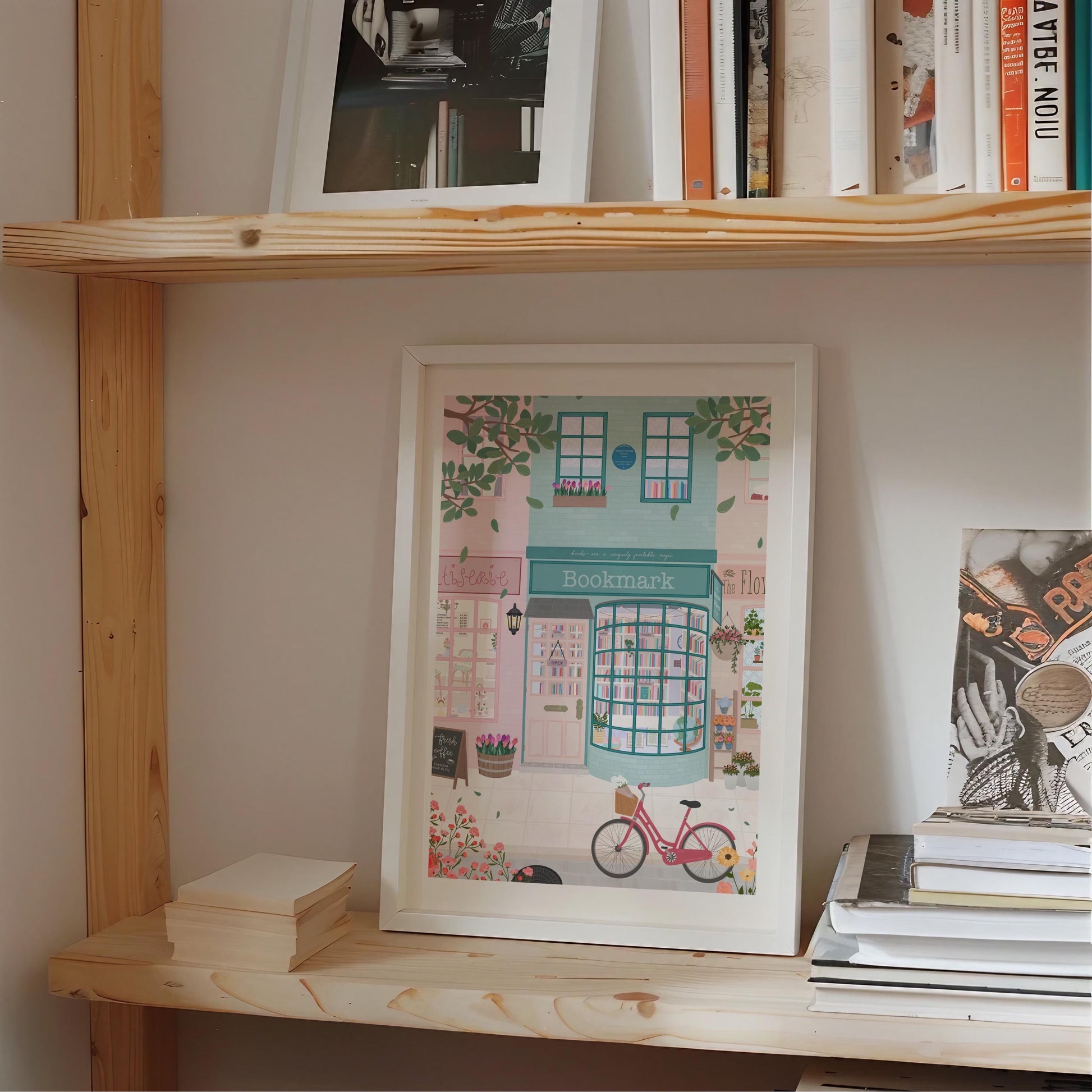 Wooden shelf with books and a framed picture of a bookshop illustration.