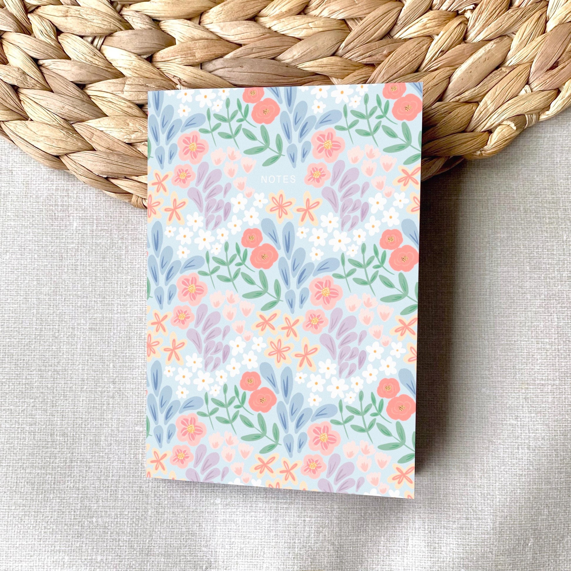 Floral patterned notepad on a woven mat