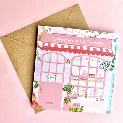 Birthday card with a pink bakery illustration and envelope on a pink background
