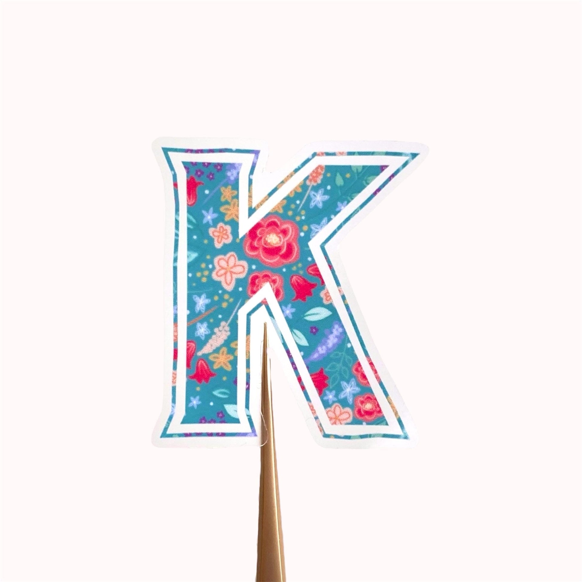 Decorative letter 'K' sticker with floral patterns on a white background