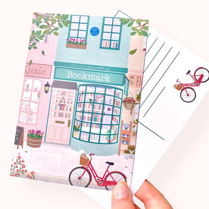 Postcard with a cute illustration of a bookshop and bicycle on a white background