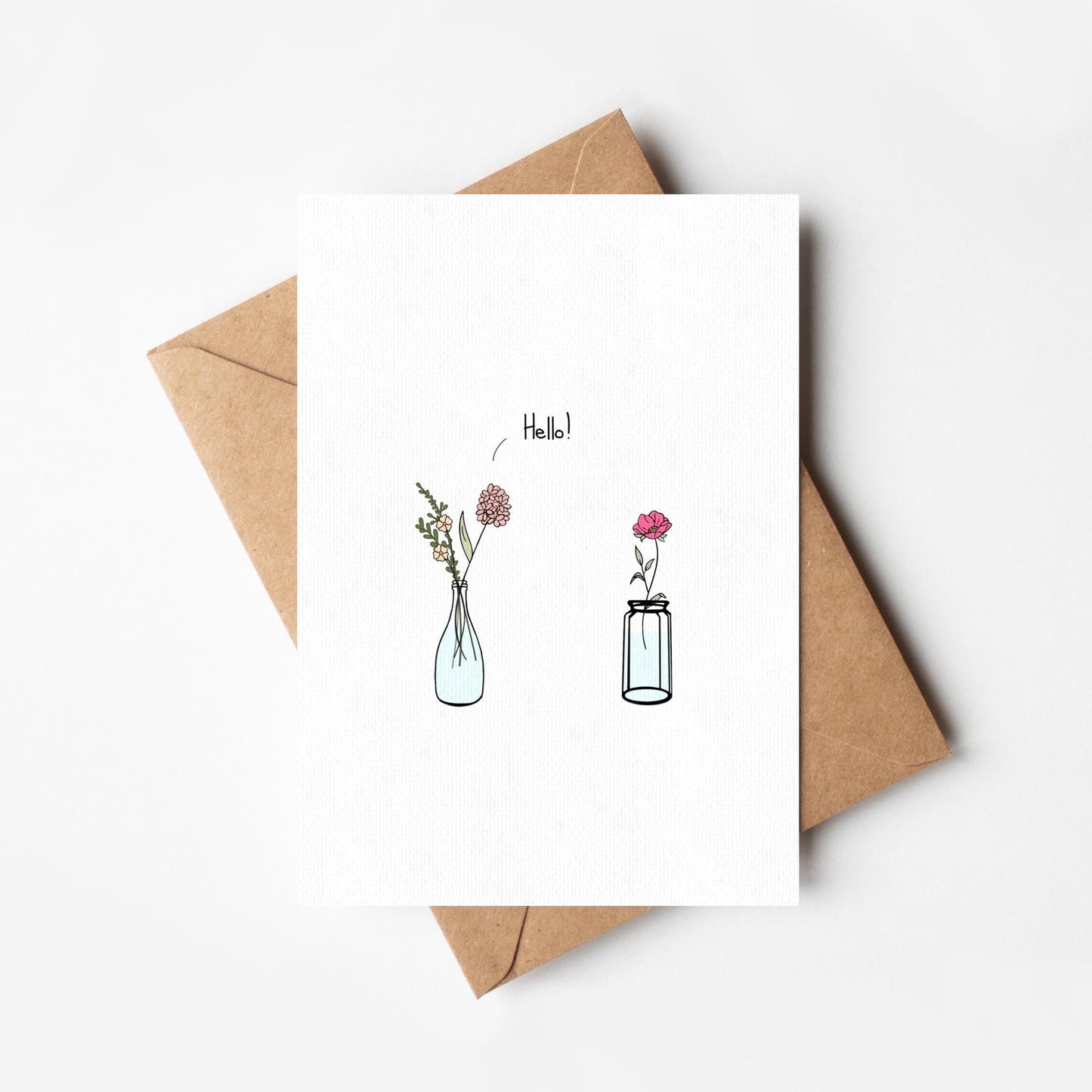 Greeting card with floral illustrations and 'Hello!' text, accompanied by a brown envelope on a white background.