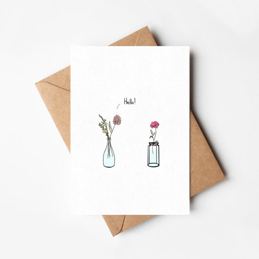 Greeting card with floral illustrations and 'Hello!' text, accompanied by a brown envelope on a white background.