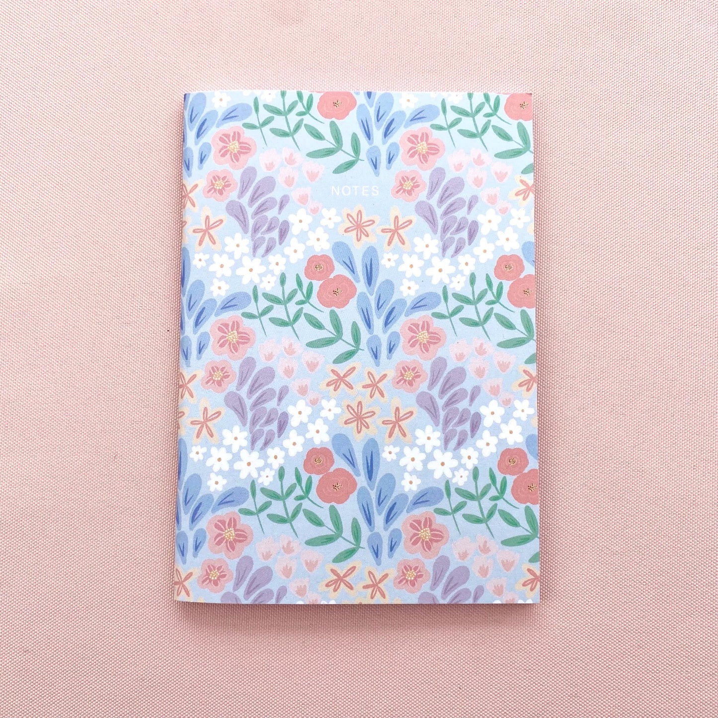 Floral patterned notebook on a pink background