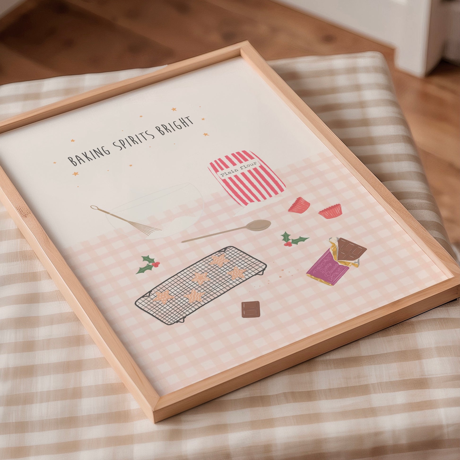 Framed artwork with pink baking-themed illustrations on a pink gingham tablecloth surface