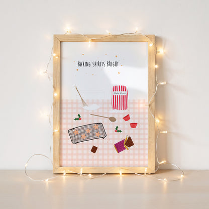 Framed artwork with Christmas baking-themed illustrations and string lights on a white wall.