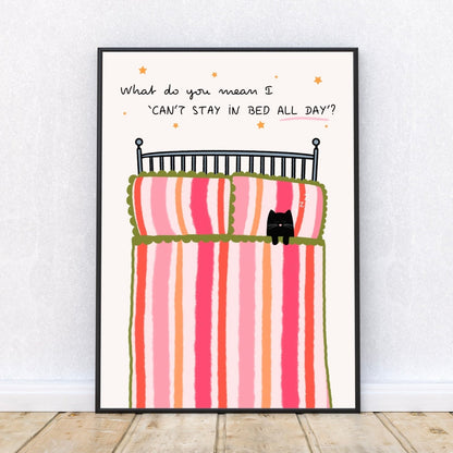 Framed artwork of a bed with striped bedding and a cat, on a white wall, with a quote 'What do you mean I 'can't stay in bed all day'' surrounded by stars.