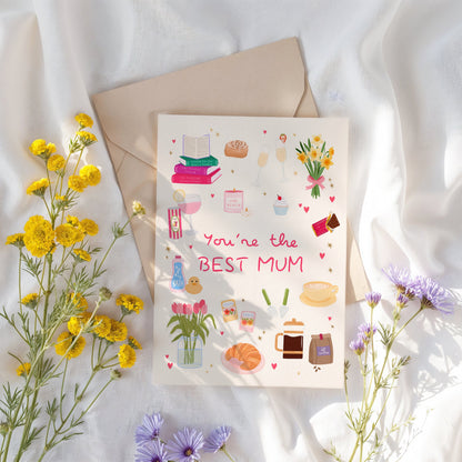 Greeting card with 'You're the BEST MUM' text surrounded by flowers on a light fabric background