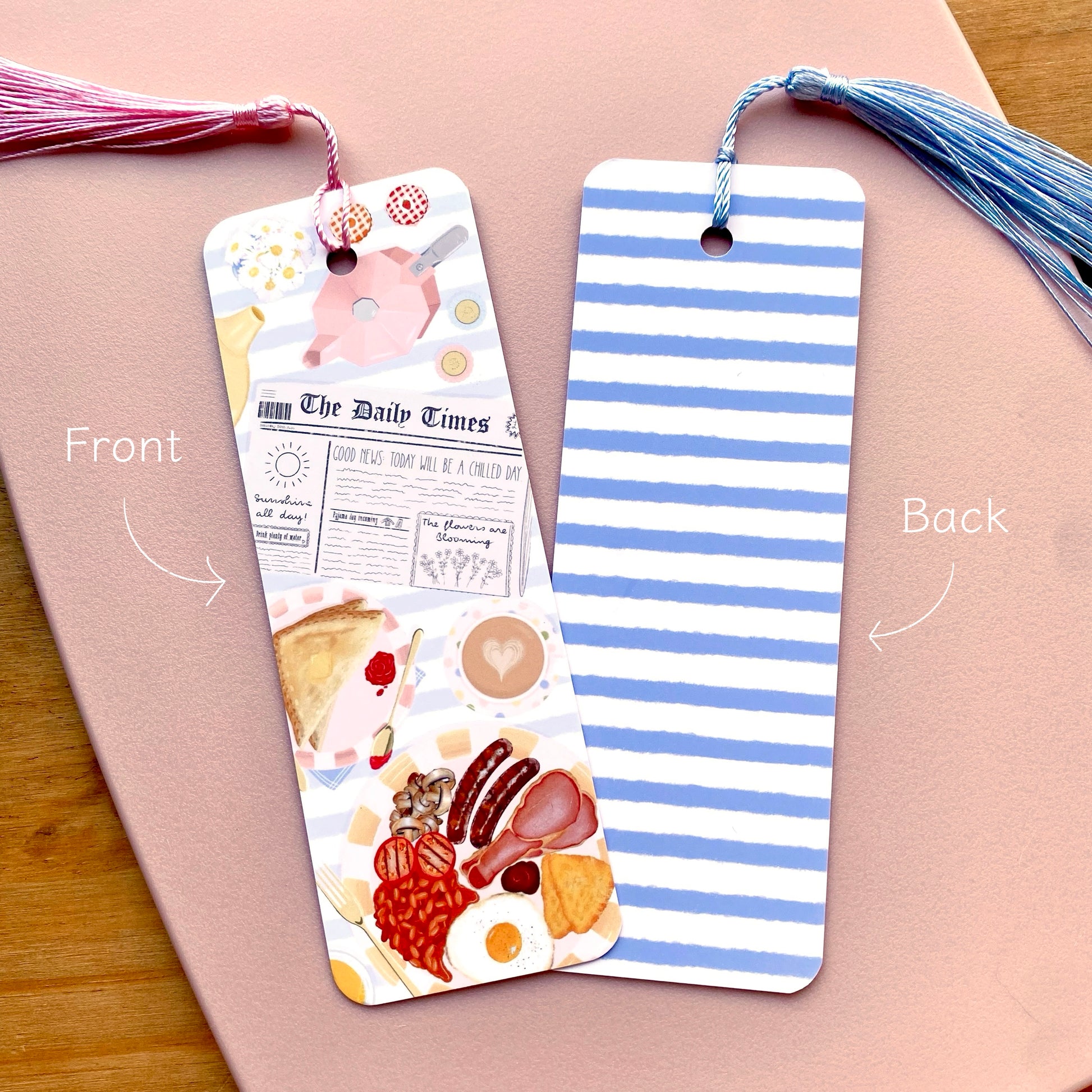 Two bookmarks showing the front and back designs on a pink surface.
