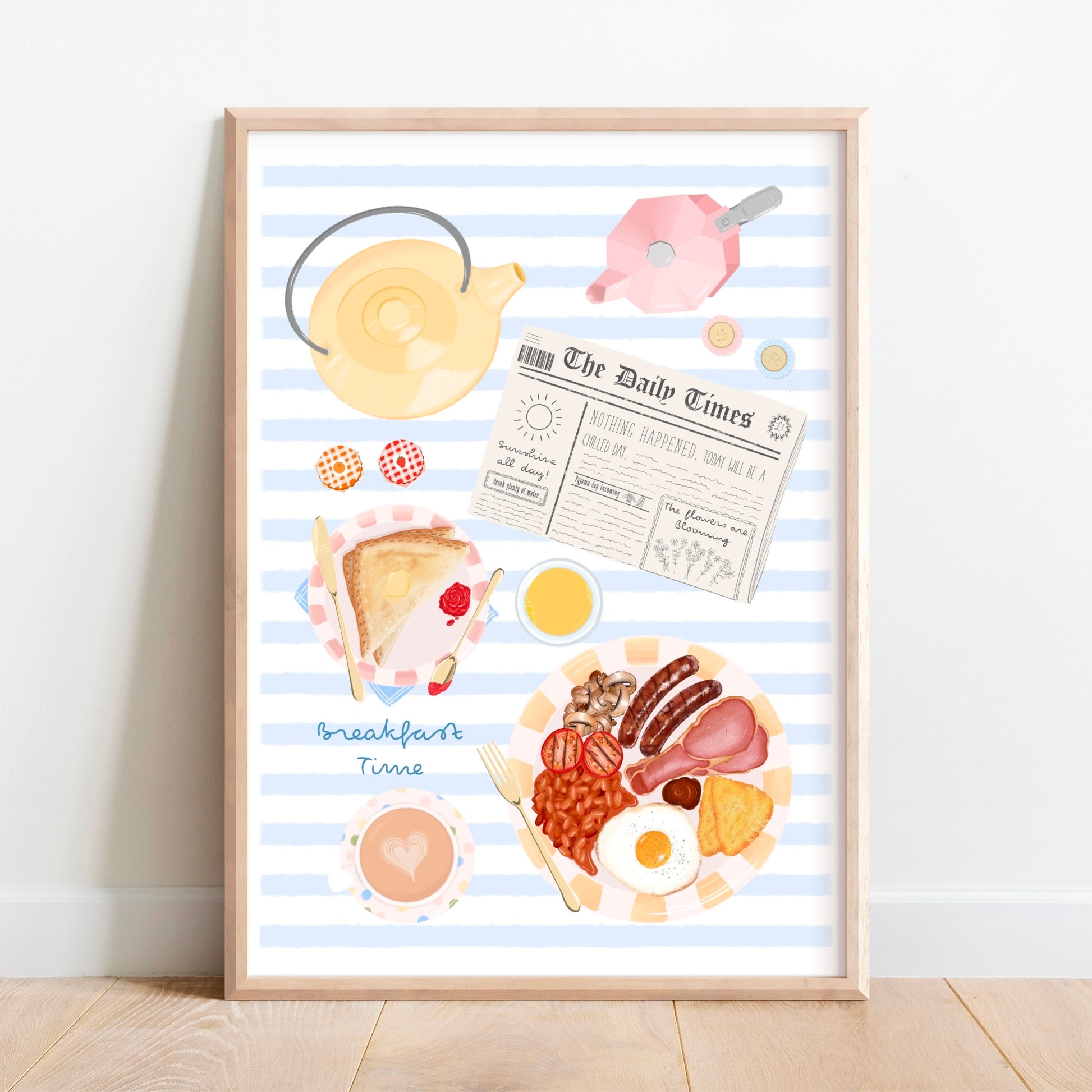 A framed art print featuring a whimsical illustration of a breakfast scene with blue and white stripes, a yellow teapot, a newspaper, toast, eggs, bacon, beans, and a cup of coffee, leaning against a white wall on a light wood floor.