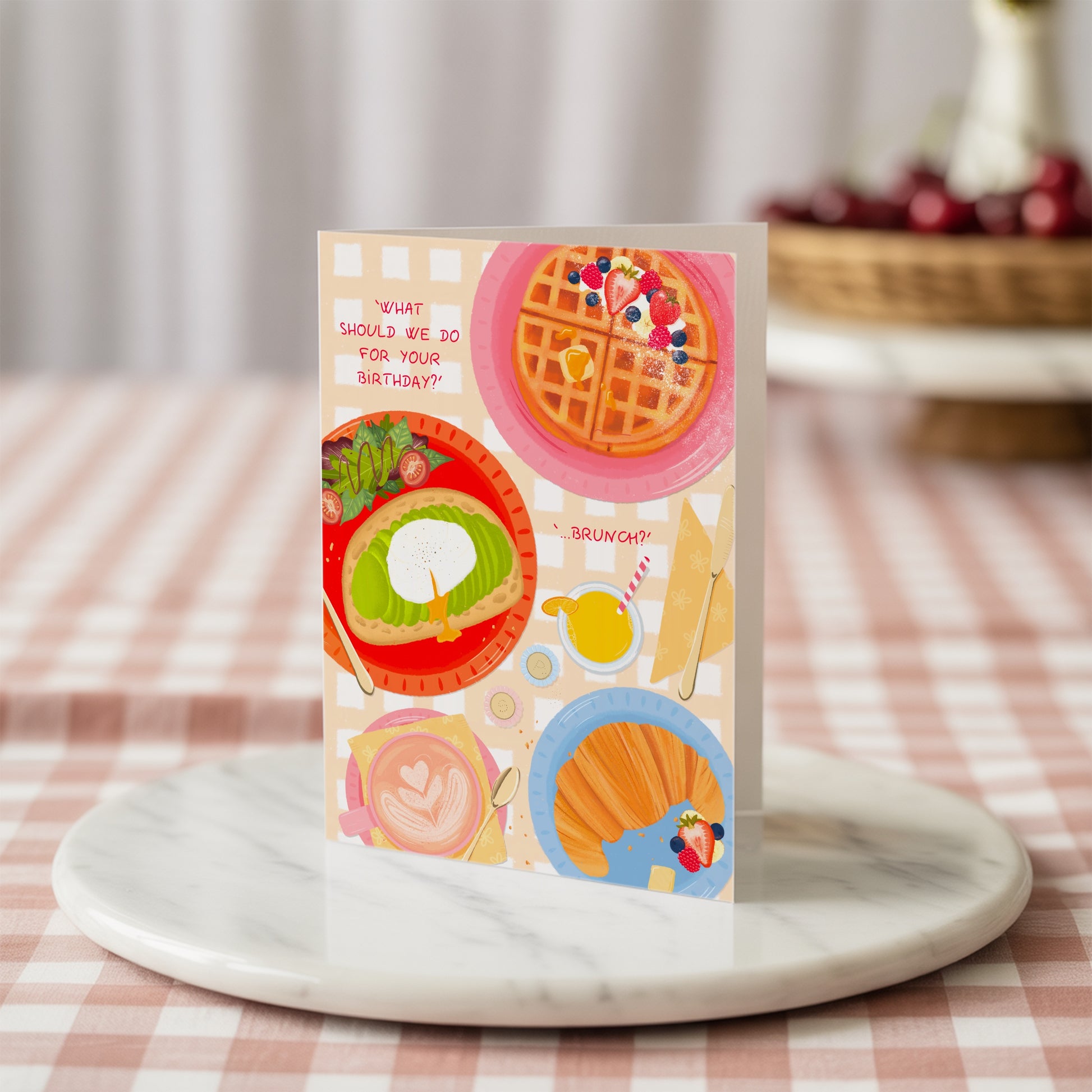 Colourful birthday greeting card with waffles and avocado toast design on a marble surface with a checkered tablecloth background