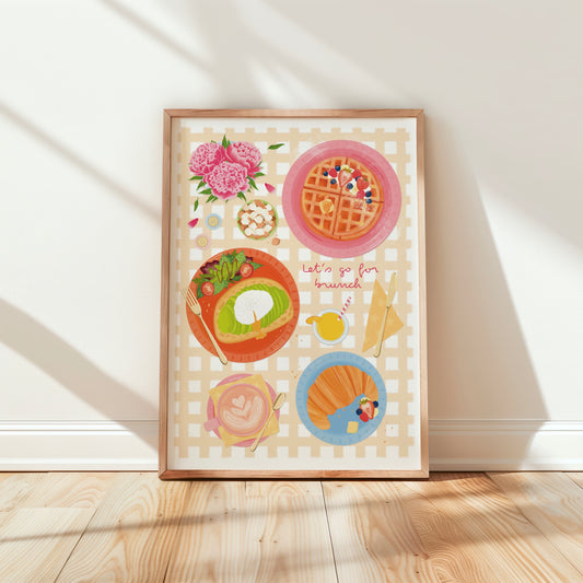 Framed artwork with illustrations of brunch food on a yellow checkered background, placed on a wooden floor.