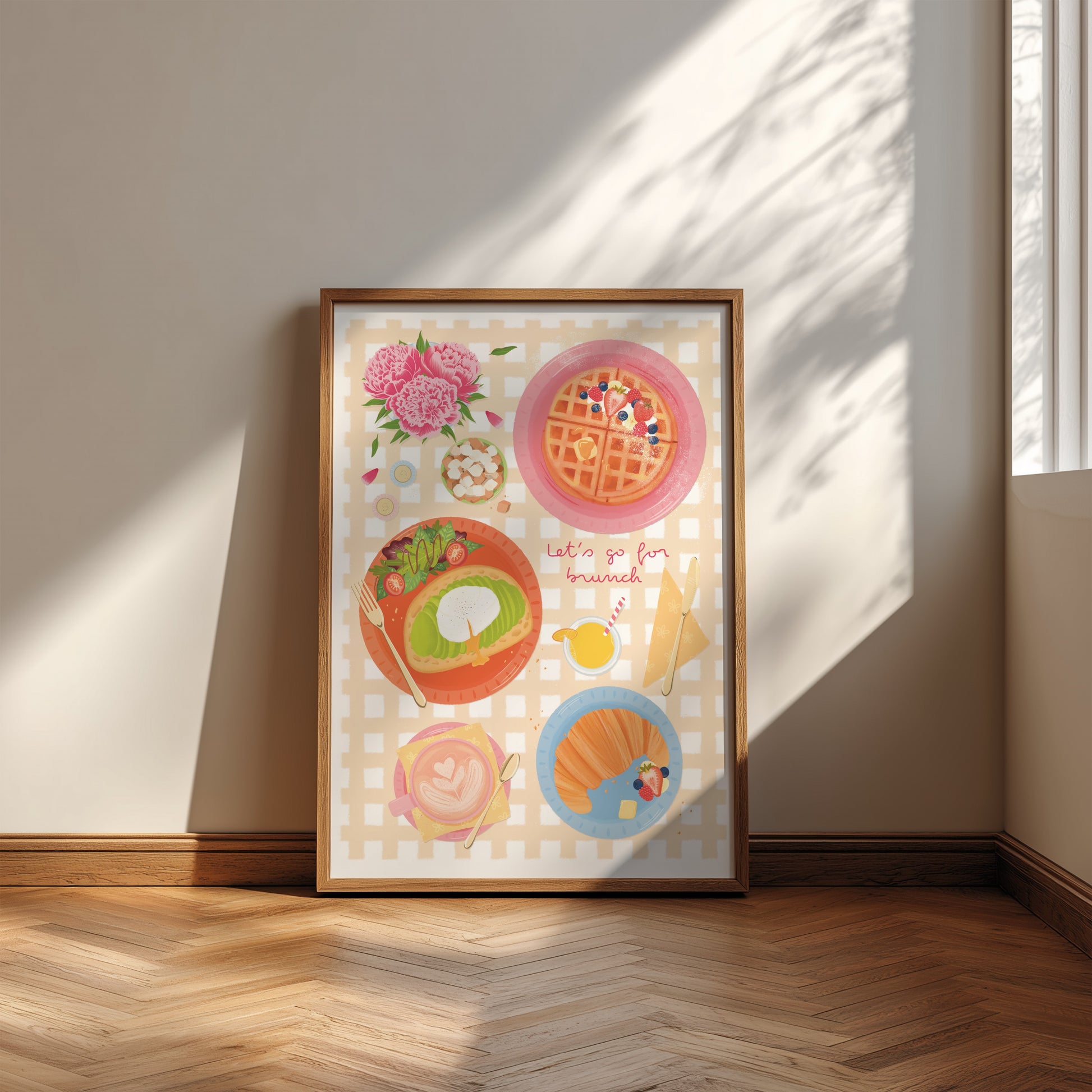 Framed artwork of brunch food illustrations on a wall with sunlight casting shadows.