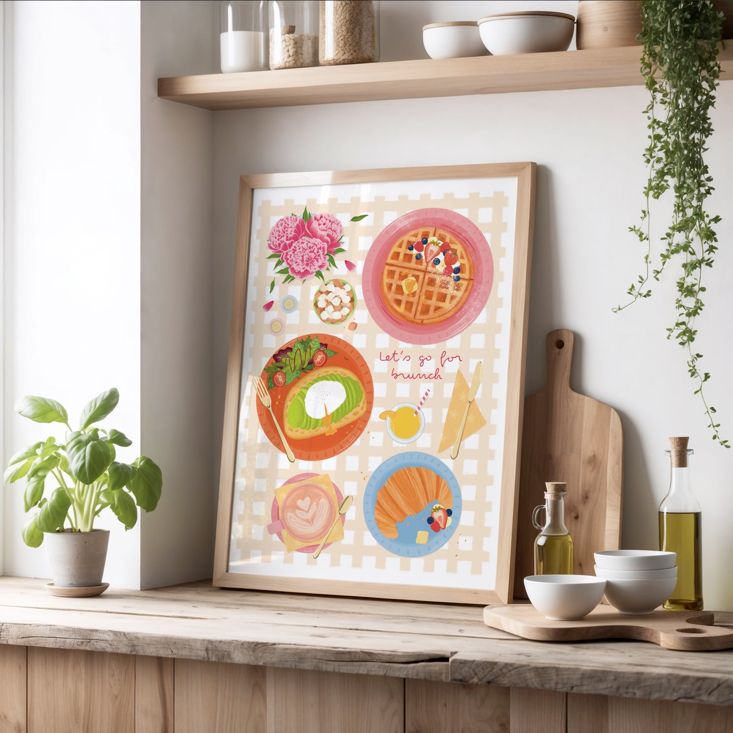Framed artwork of illustrated brunch items, on a kitchen counter with plants and kitchenware.