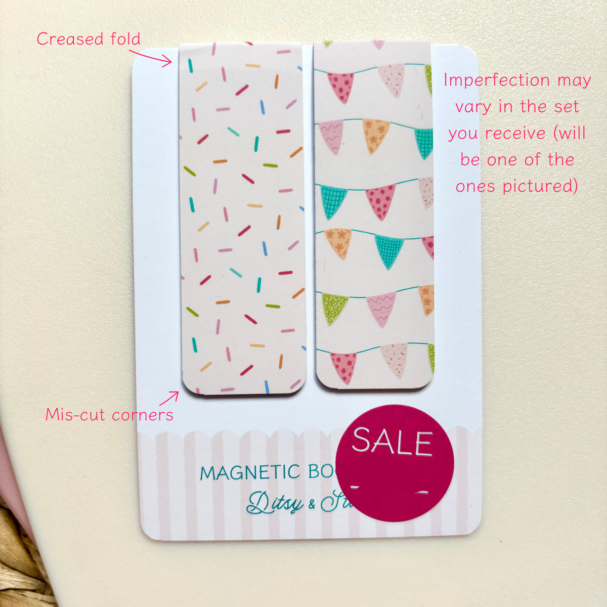 A set of two decorative magnetic bookmarks on a white backing card, photographed against a light cream background. One bookmark has multicoloured confetti on a white base, and the other has colourful bunting flags.