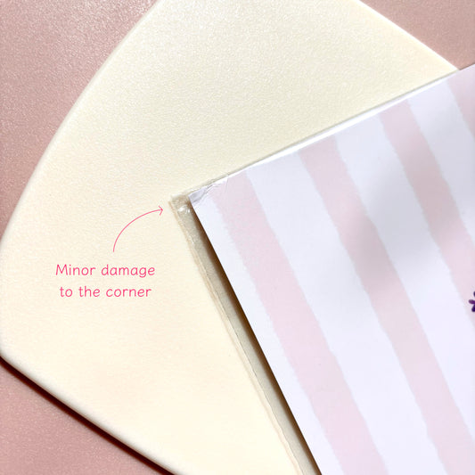 A close-up of a pink striped print, showing minor damage to the corner with a pink text overlay.