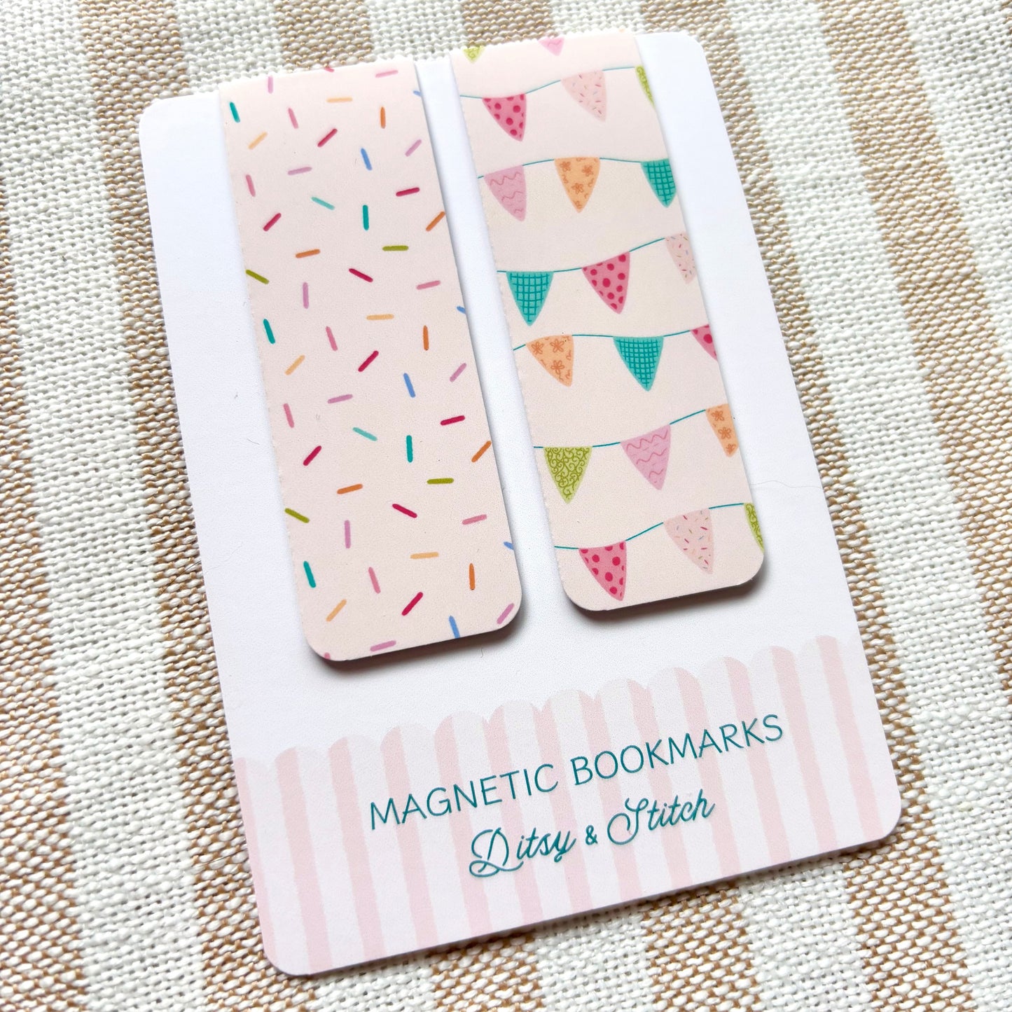 Two magnetic bookmarks with colourful bunting and sprinkles designs on a striped fabric background