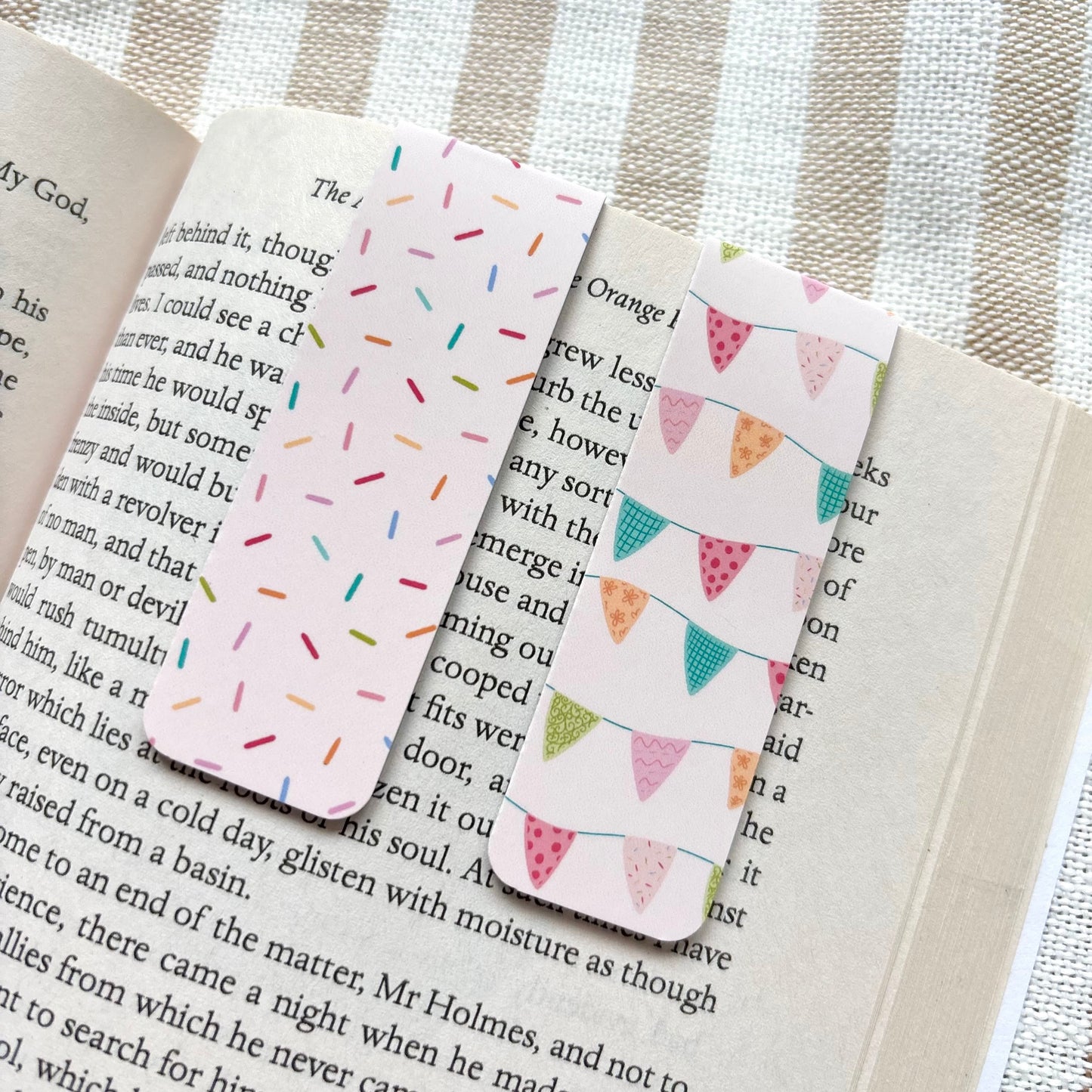 Two patterned bookmarks on an open book with a striped background