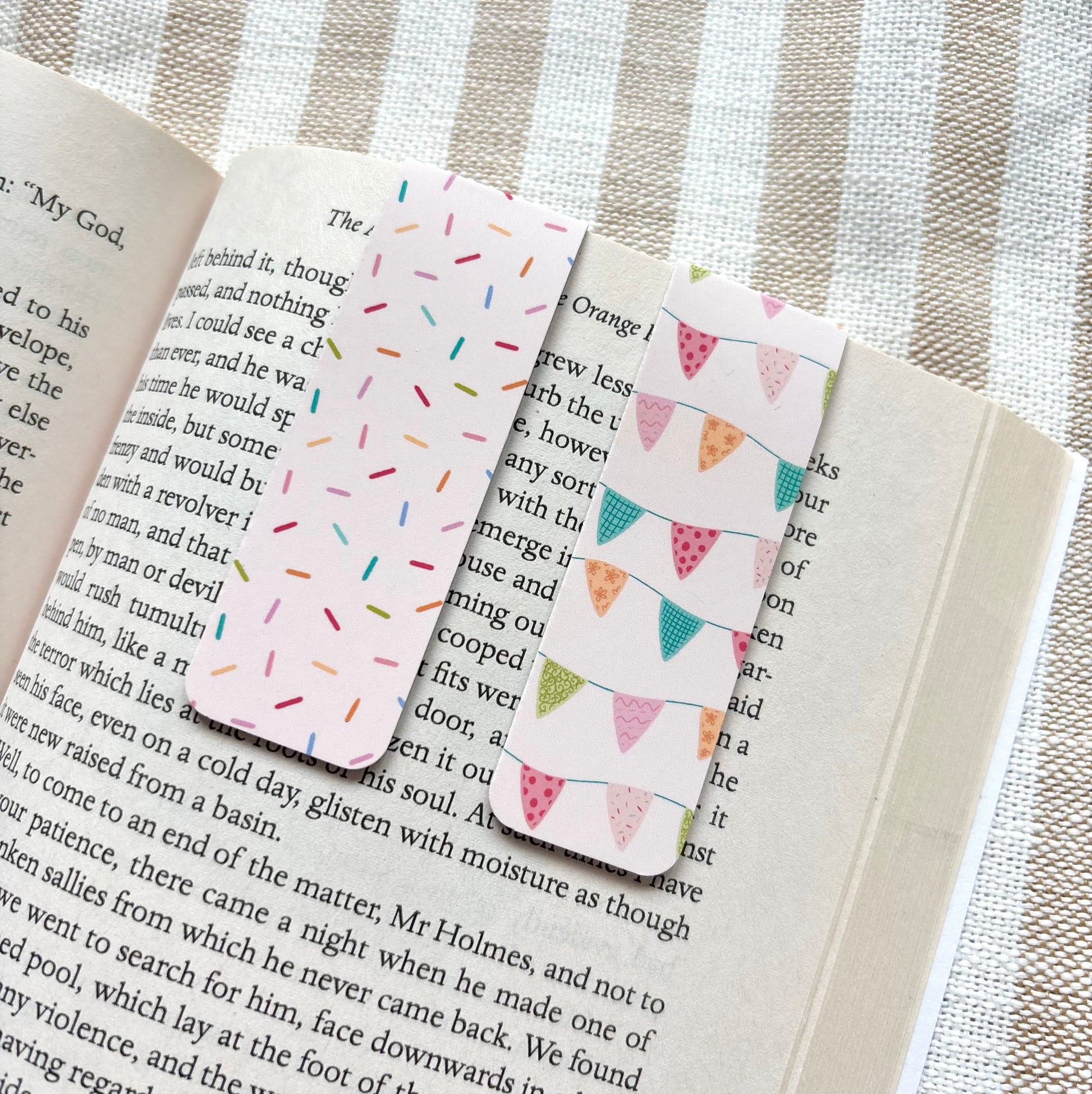 Two patterned bookmarks on an open book with a striped fabric background