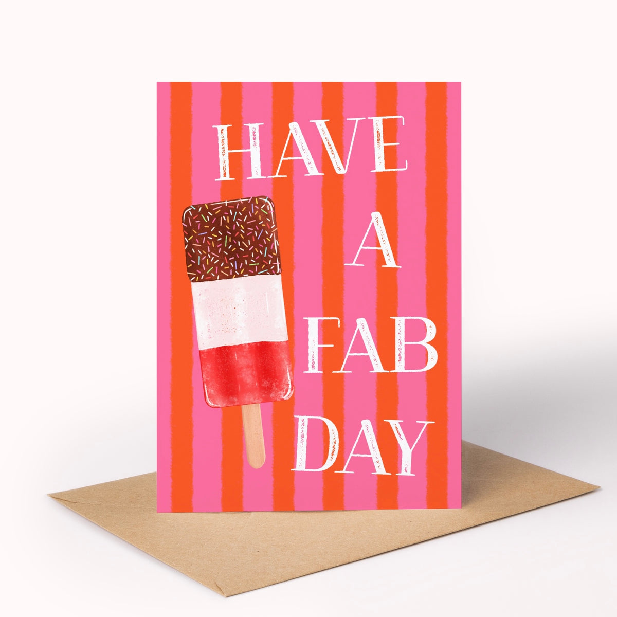 A greeting card with a brown kraft envelope, featuring a pink and orange striped background, an ice lolly, and the text 'HAVE A FAB DAY' in white.