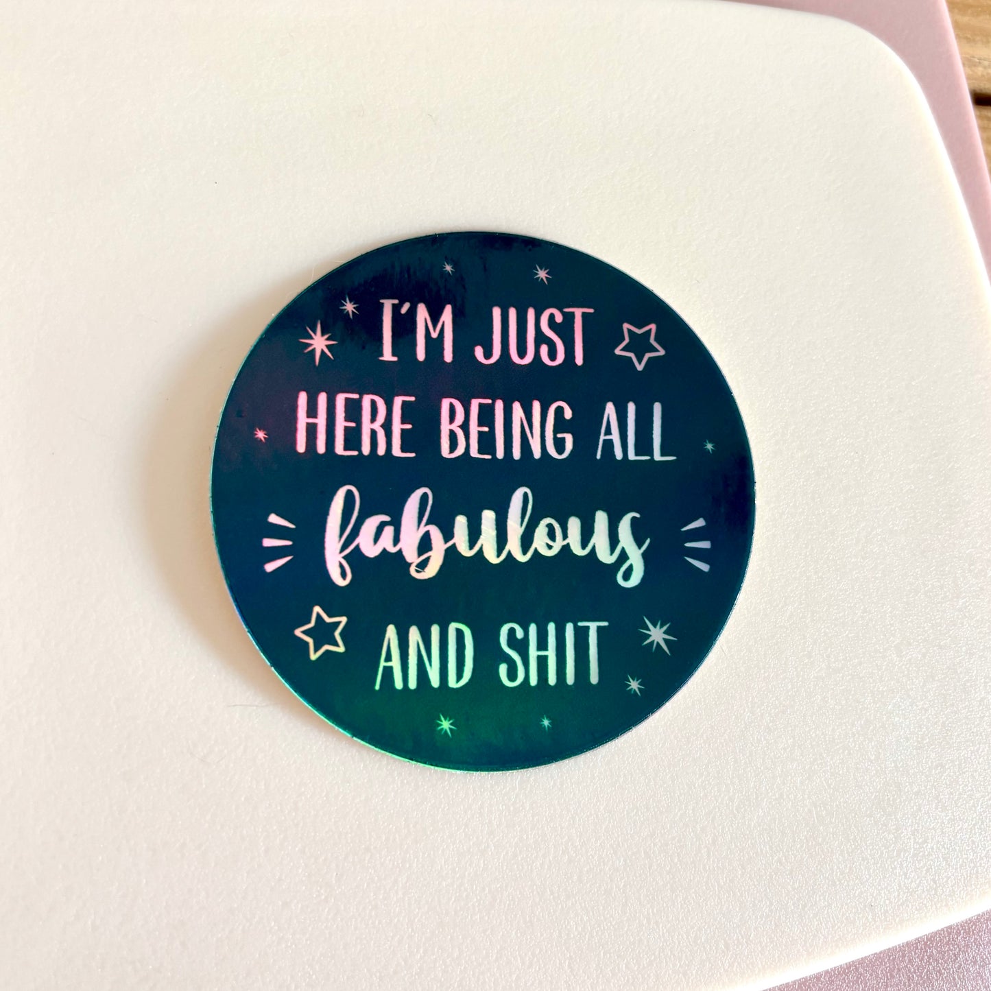 A round sticker with a dark teal and black gradient background featuring the text 'I'M JUST HERE BEING ALL fabulous AND SHIT' in white holographic lettering, surrounded by small white stars.