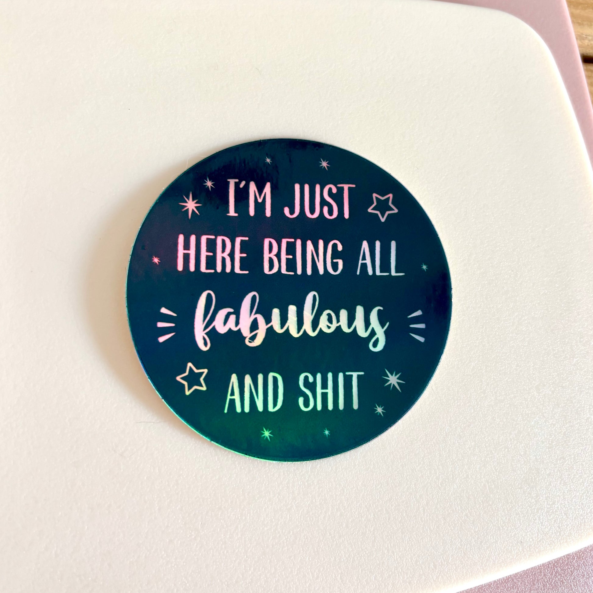 A round sticker with a dark teal and black gradient background featuring the text 'I'M JUST HERE BEING ALL fabulous AND SHIT' in white holographic lettering, surrounded by small white stars.