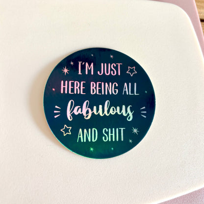 A round sticker with a dark teal and black gradient background featuring the text 'I'M JUST HERE BEING ALL fabulous AND SHIT' in white holographic lettering, surrounded by small white stars.