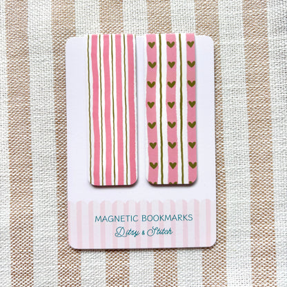 Magnetic bookmarks with pink and gold striped design on a striped fabric background