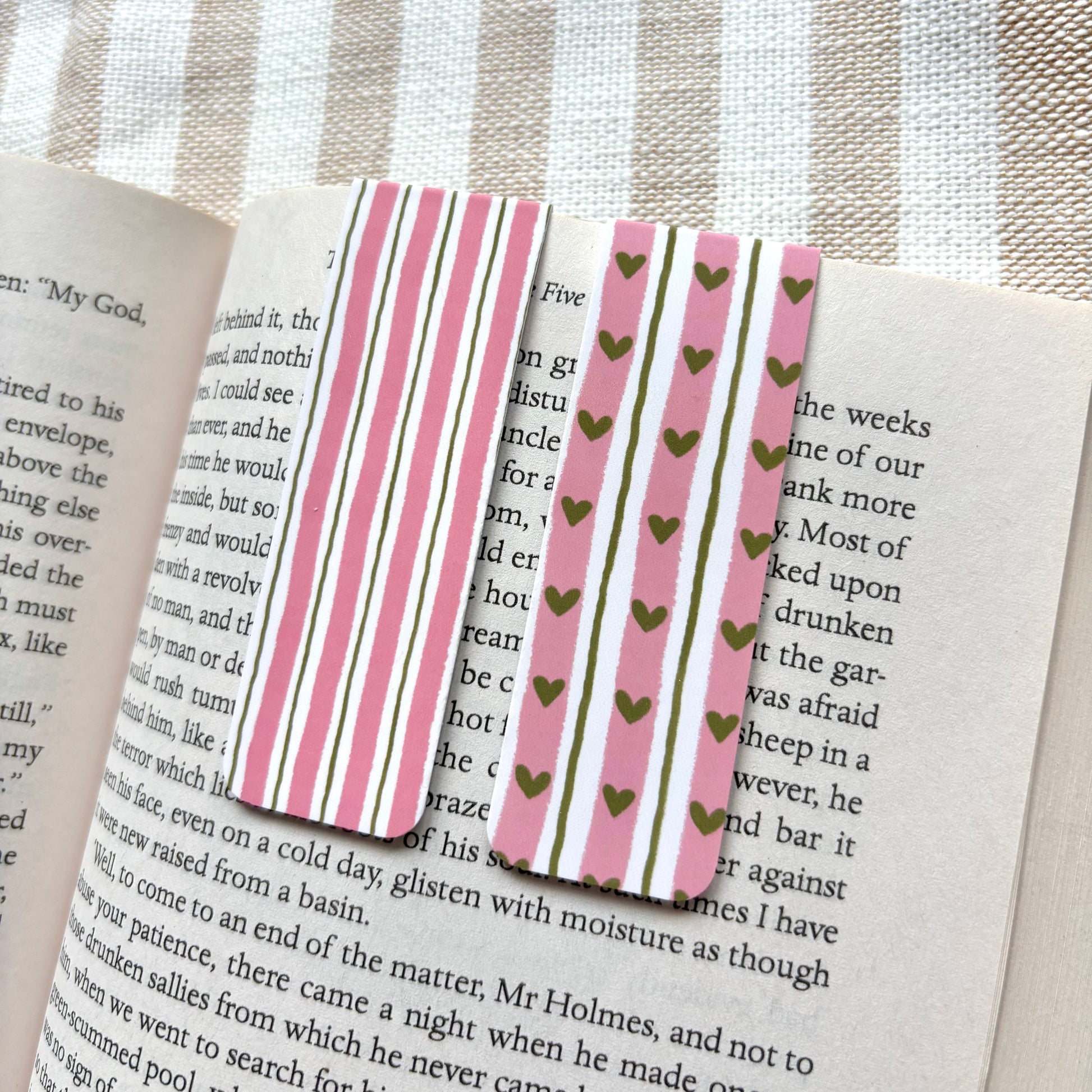 Striped and heart-patterned bookmark on an open book with a striped fabric background
