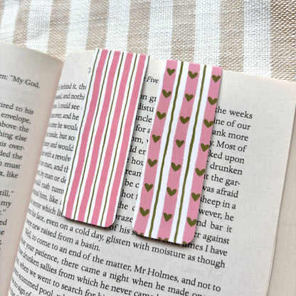 Striped and heart-patterned bookmark on an open book with a striped fabric background