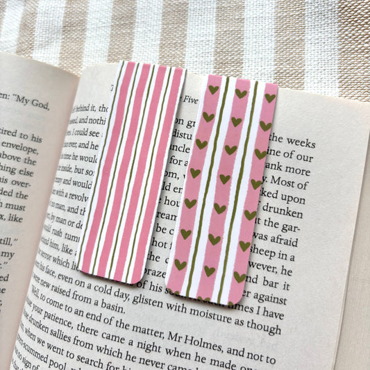 Striped and heart-patterned bookmark on an open book with a striped fabric background