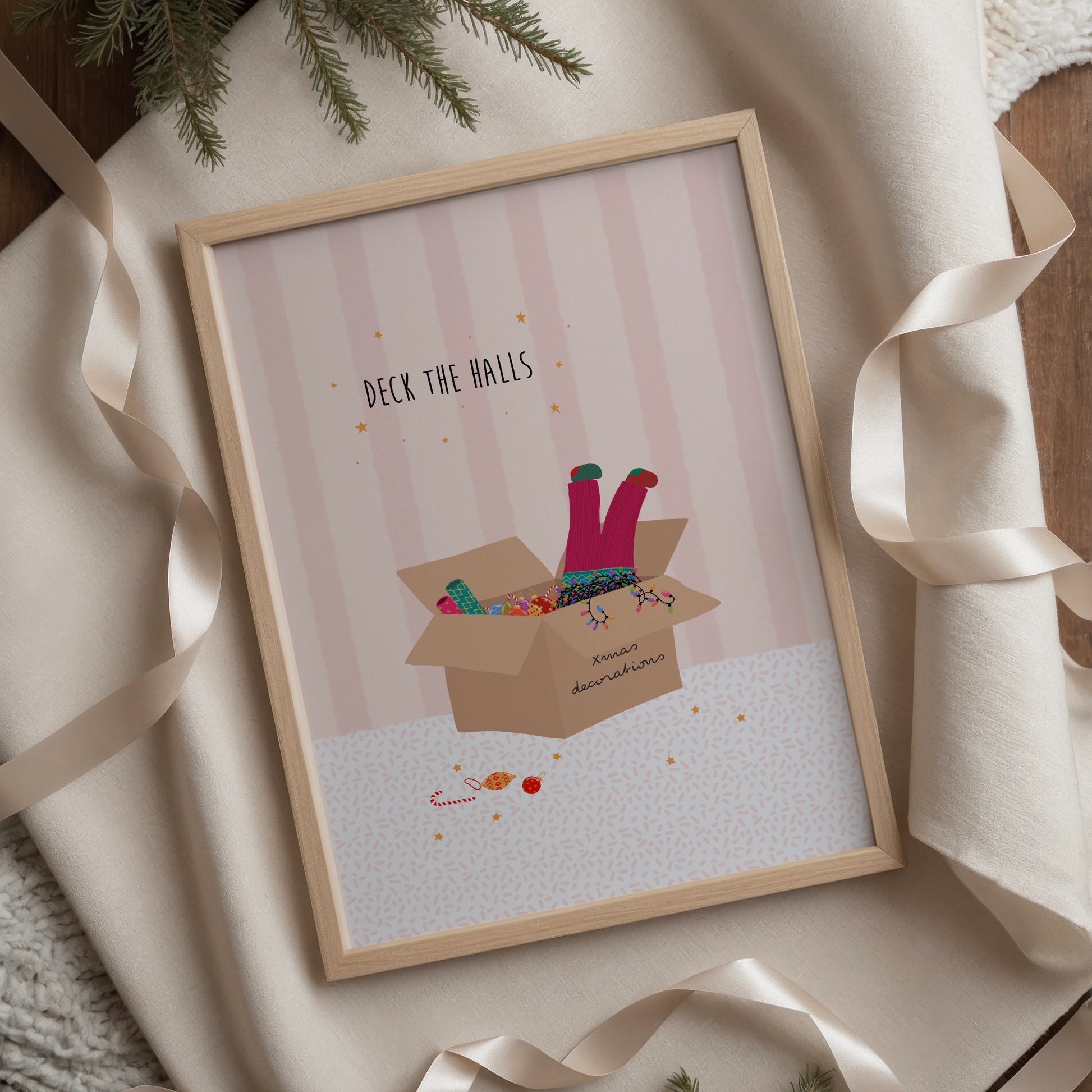 A pink striped illustration with a box of Christmas decorations and colourful lights and a girls legs in pink trousers and mismatched socks dangling out of the top