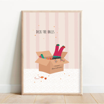 Framed artwork with a cardboard box and legs peeking out, on a light pink background.