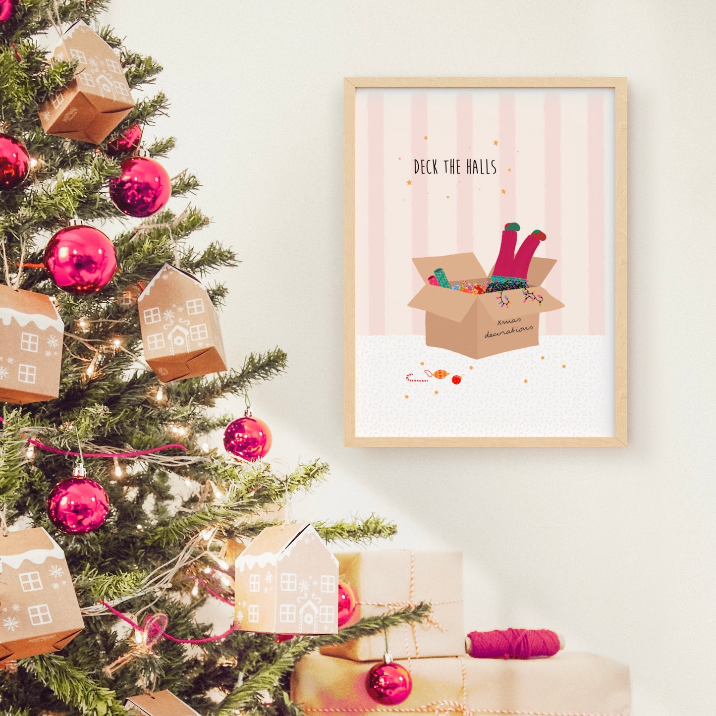 Framed artwork with a Christmas theme next to a decorated Christmas tree.