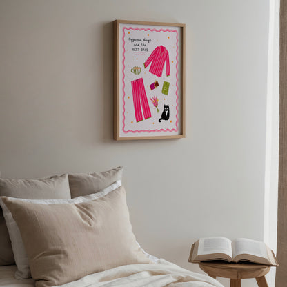 Framed pink pyjamas artwork on a wall above a bed with pillows and an open book on a small table.