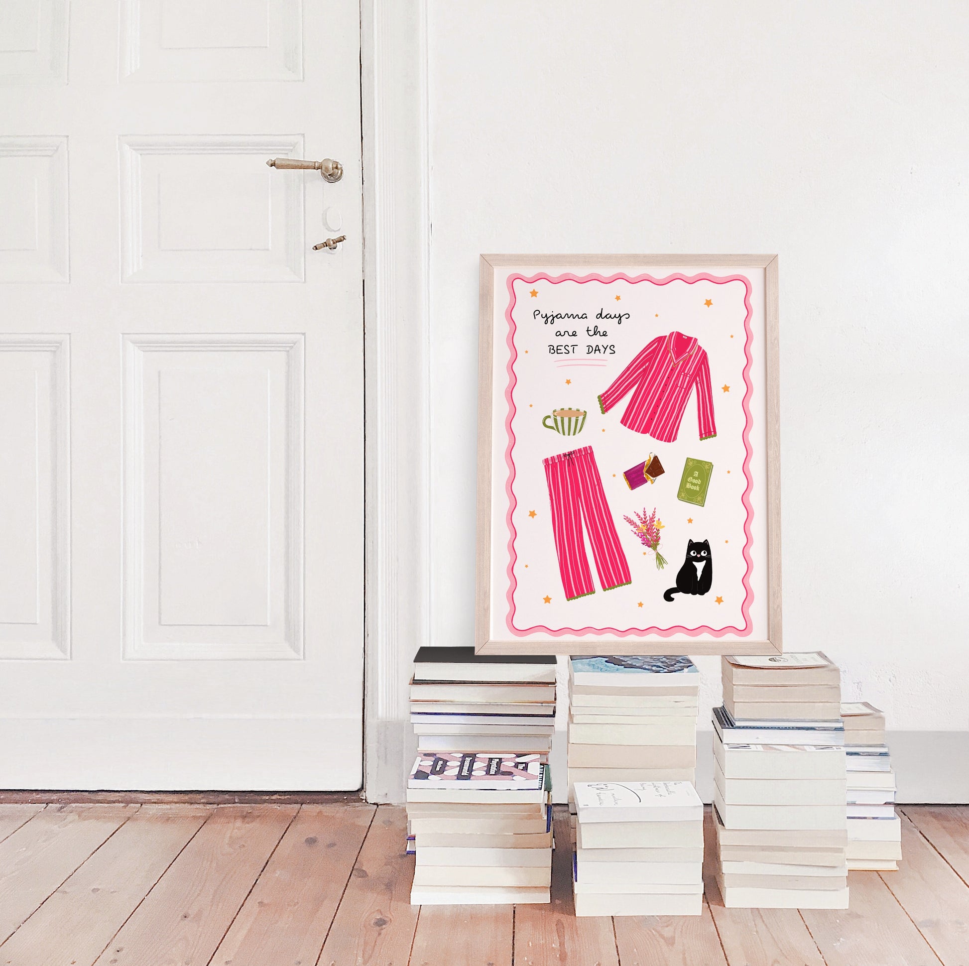 Framed artwork with pink striped pyjamas on a white wall above stacked books.