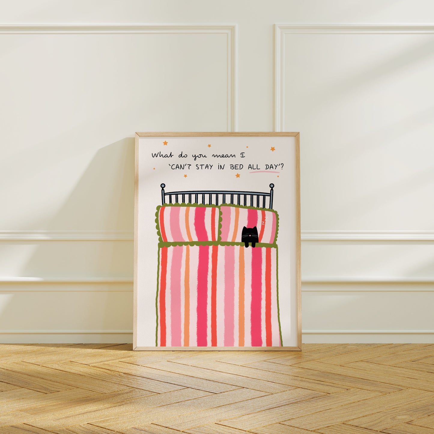 Framed artwork with a cartoon of a cat in bed and text on a white wall.