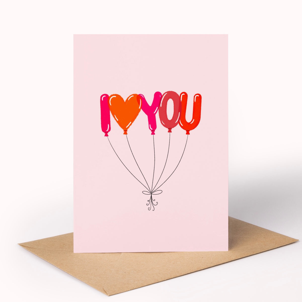 A pink greeting card with a brown envelope, featuring the text 'I <heart> YOU' formed by colourful balloon shapes in pink, orange, and red.
