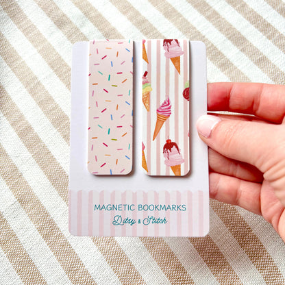 Hand holding a set of magnetic bookmarks with ice cream and sprinkles designs on a striped fabric background
