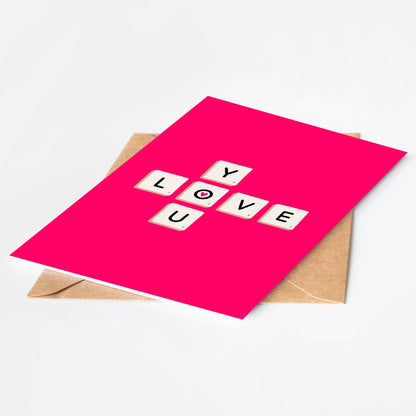 Pink card with 'LOVE YOU' in scrabble tiles on a white background