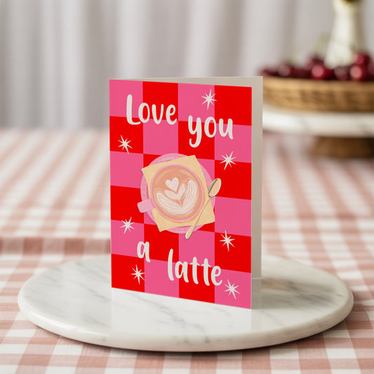 Card with 'Love you a latte' design on a red and pink checkered background with stars.