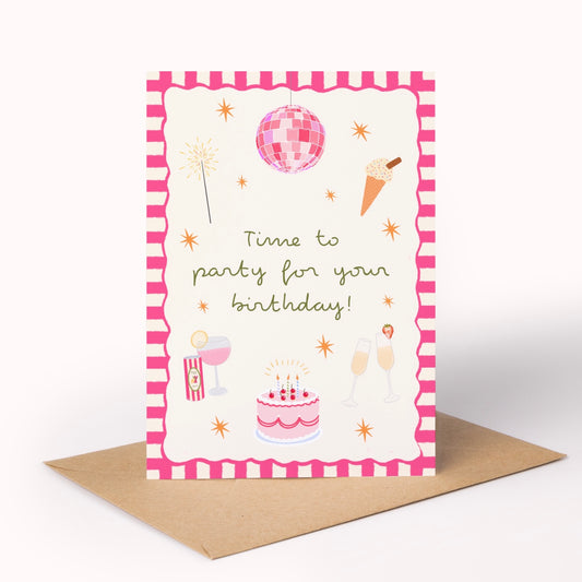 A birthday greeting card with a pink and white patterned border, featuring illustrations of a disco ball, fireworks, an ice cream cone, a cake, champagne glasses, and the text 'Time to party for your birthday!'. The card is displayed upright on a brown kraft envelope against a clean white background.