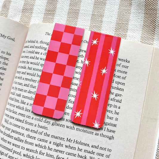 Red and pink checkered bookmark set on an open book with a striped fabric background