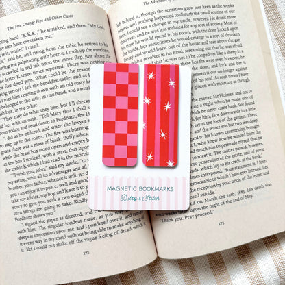 Two magnetic bookmarks on an open book with a striped fabric background