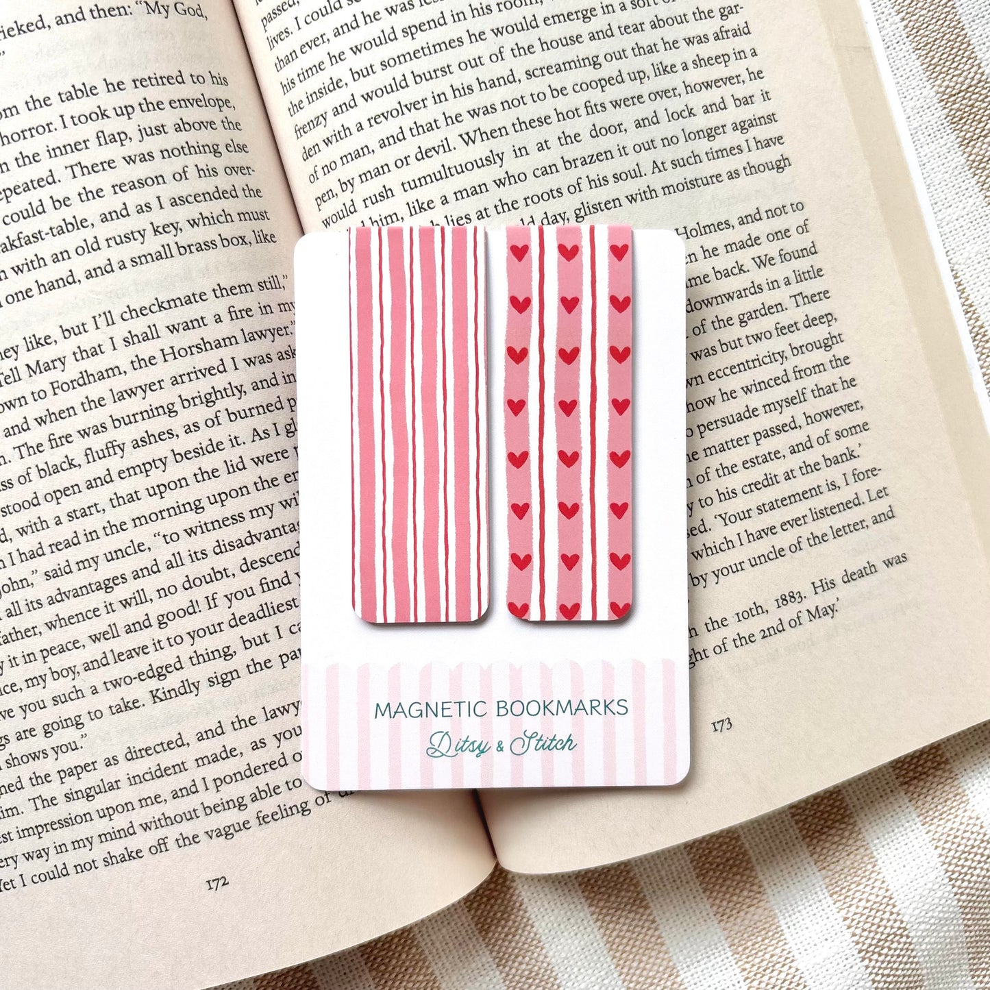 Magnetic bookmarks with heart and stripe patterns in pink and red on a book page