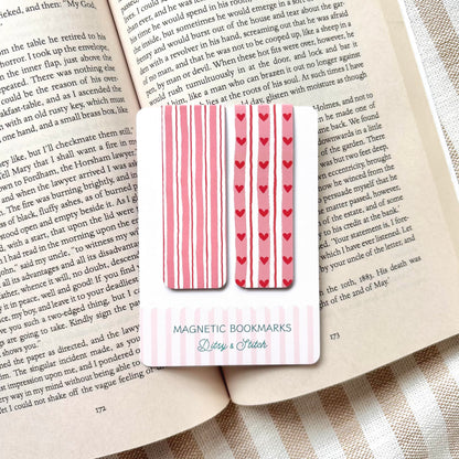 Magnetic bookmarks with heart and stripe patterns in pink and red on a book page