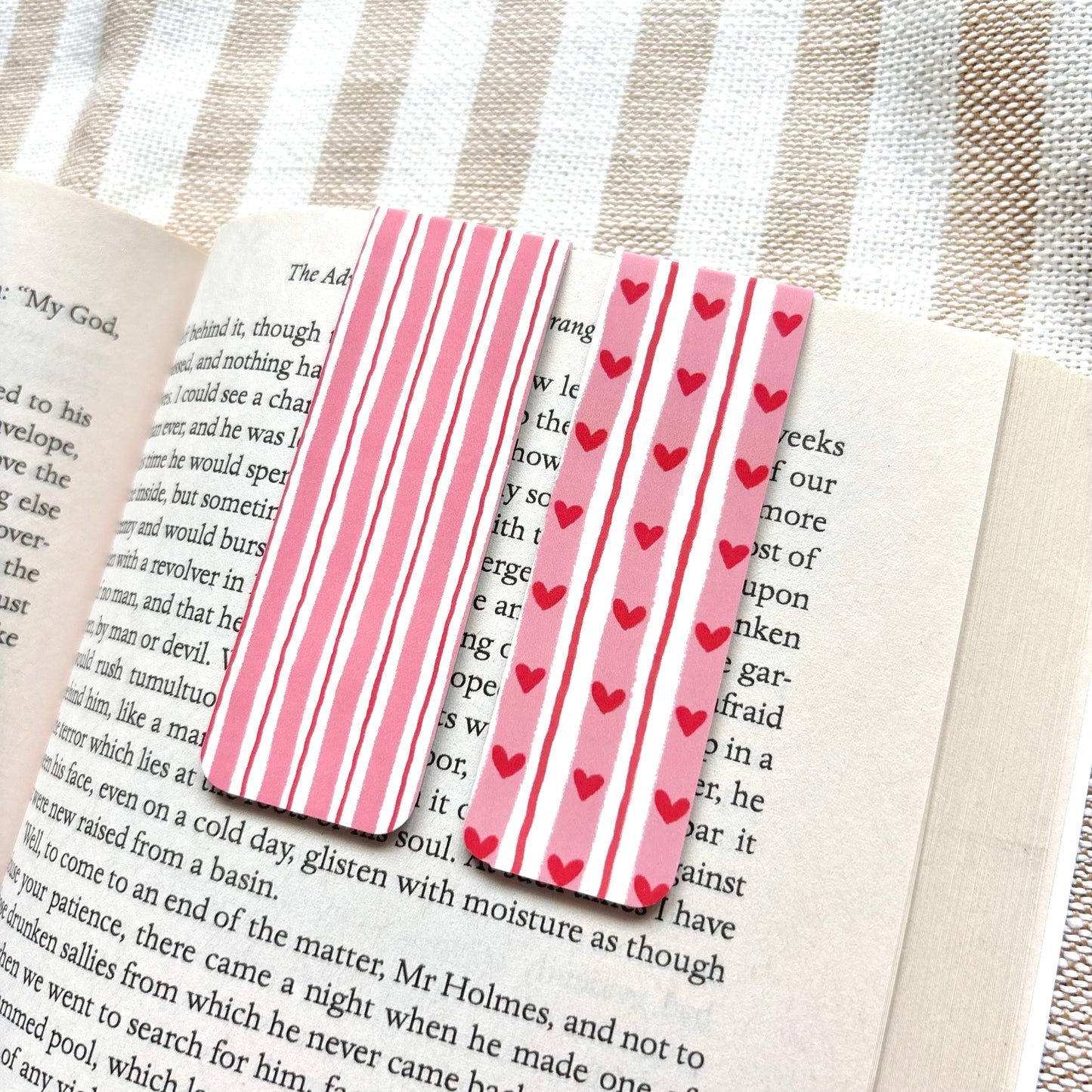 Pink striped bookmarks with red hearts on a book page.