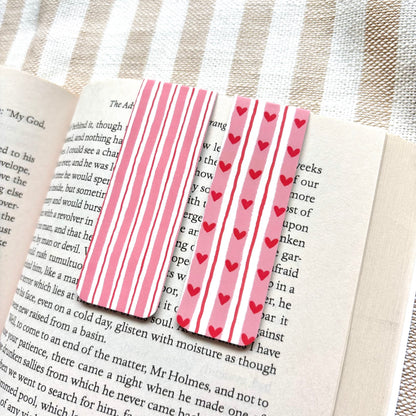Pink striped bookmarks with red hearts on a book page.